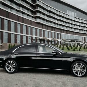 Elegant black sedan parked in front of a modern architectural building, showcasing luxury and style.